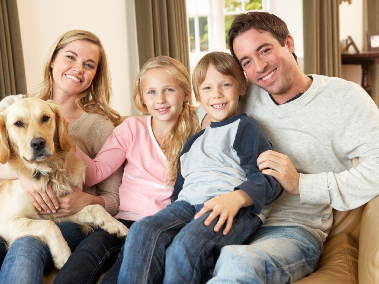 A family is sitting on a couch with a dog.