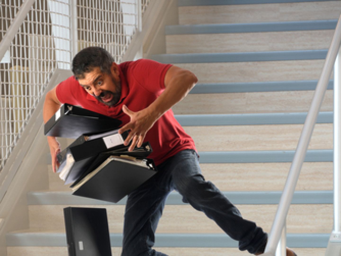 A man in a red shirt is falling down a set of stairs