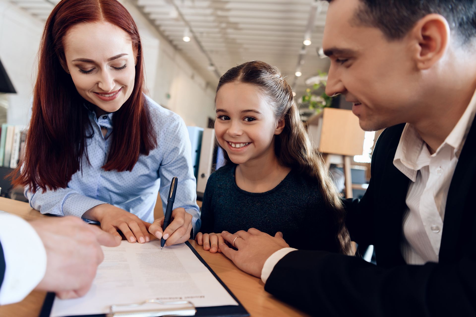 A man , woman and child are signing a document.