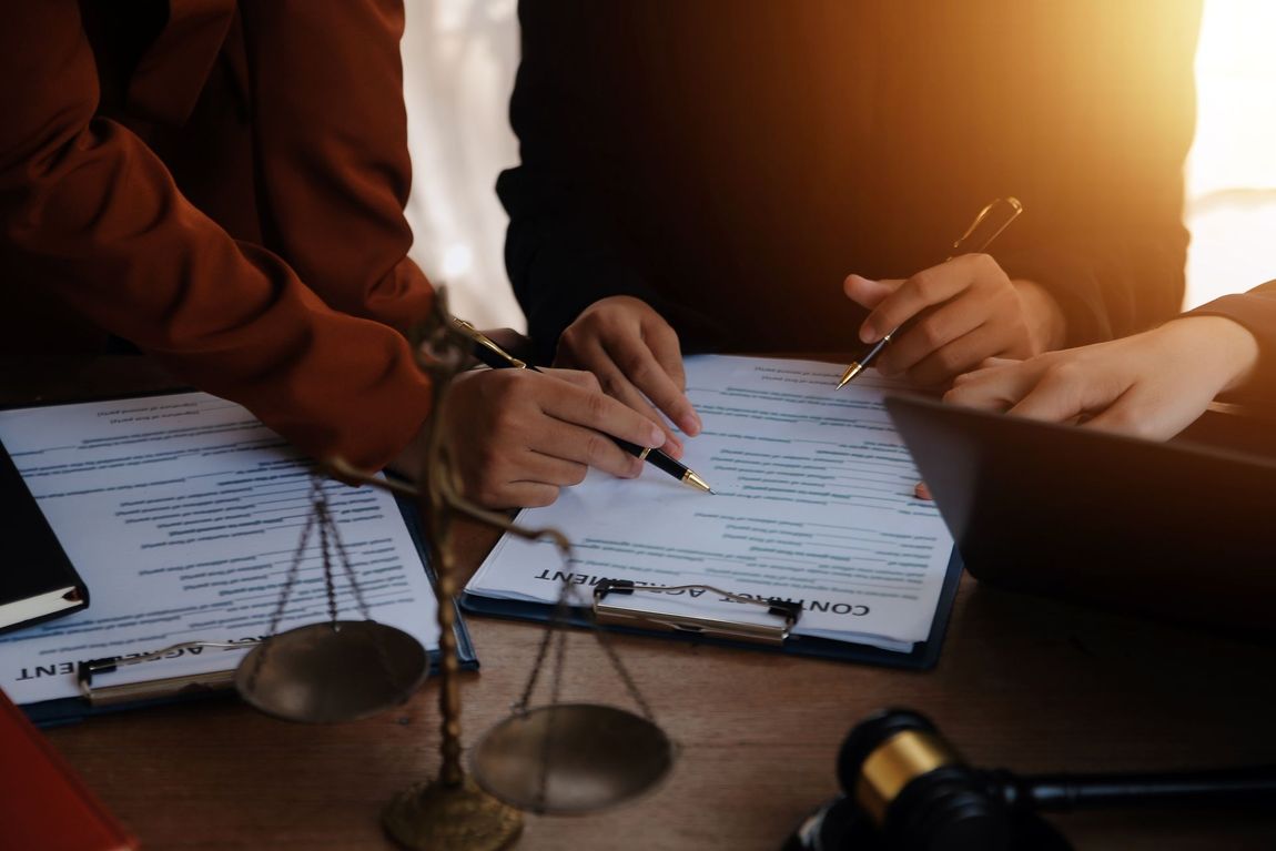 A group of people are sitting at a table with a judge 's gavel and scales of justice.