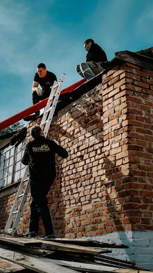 Gloved hand laying a red brick on a brick wall outdoors