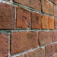 Close-up of a red brick wall with gray mortar lines and weathered texture