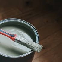 Paintbrush with white paint resting in an open paint can.