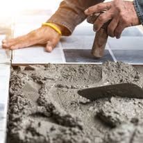 Worker smoothing wet concrete with a trowel during paving installation