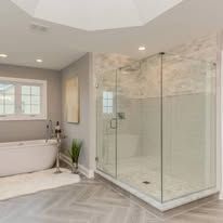 Modern bathroom with freestanding tub and large glass walk-in shower in light gray tones