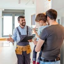 Home repair worker showing a tablet to two people in a bright kitchen