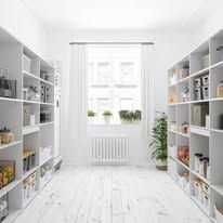 Bright white hallway with built-in shelves, a window, and a potted plant in a minimalist room