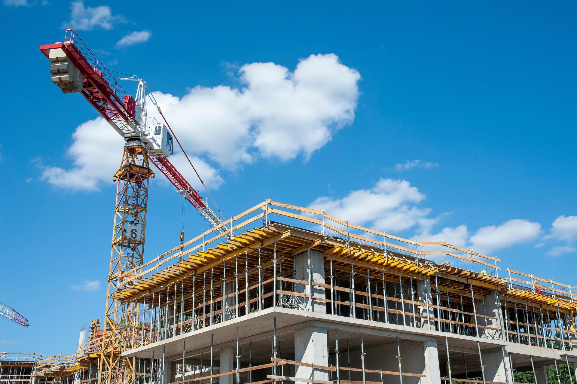 Construction site with a crane beside a partially built concrete structure under a blue sky
