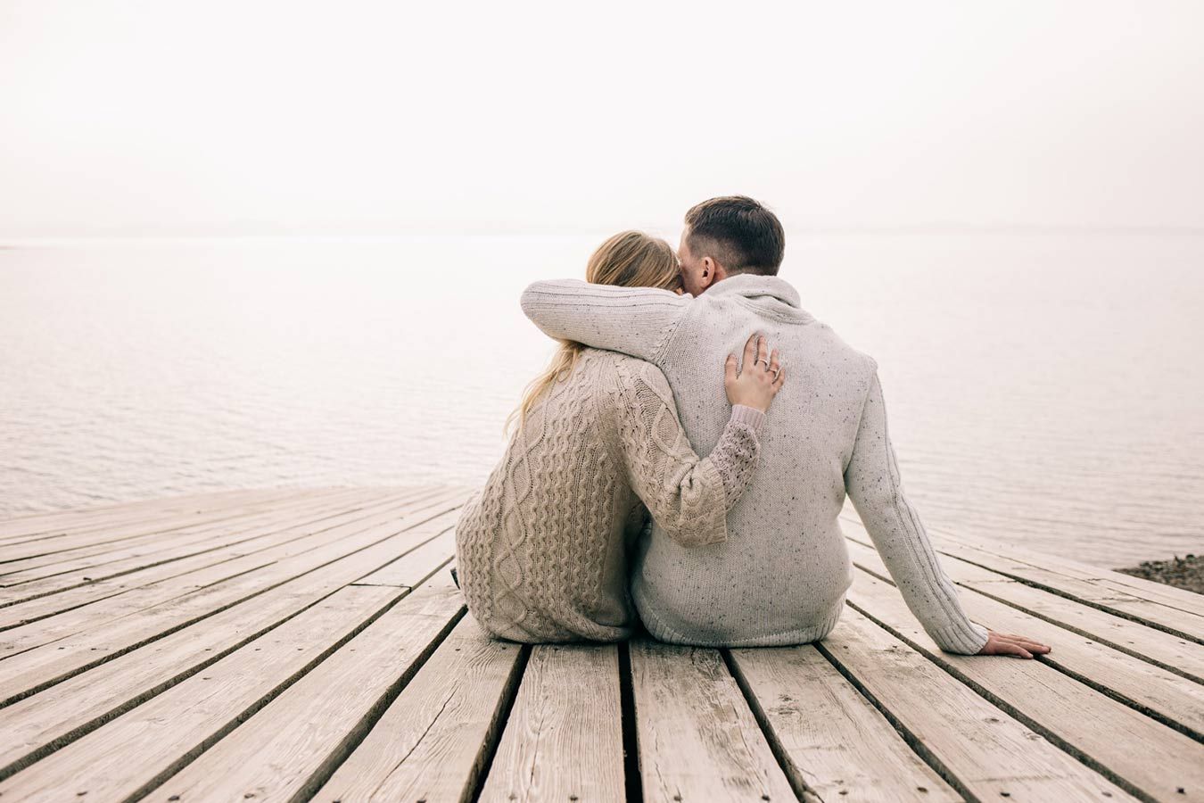 A Man and a Woman Are Sitting on a Wooden Dock Looking at the Water — Living Well Psychology Clinic in Erina, NSW
