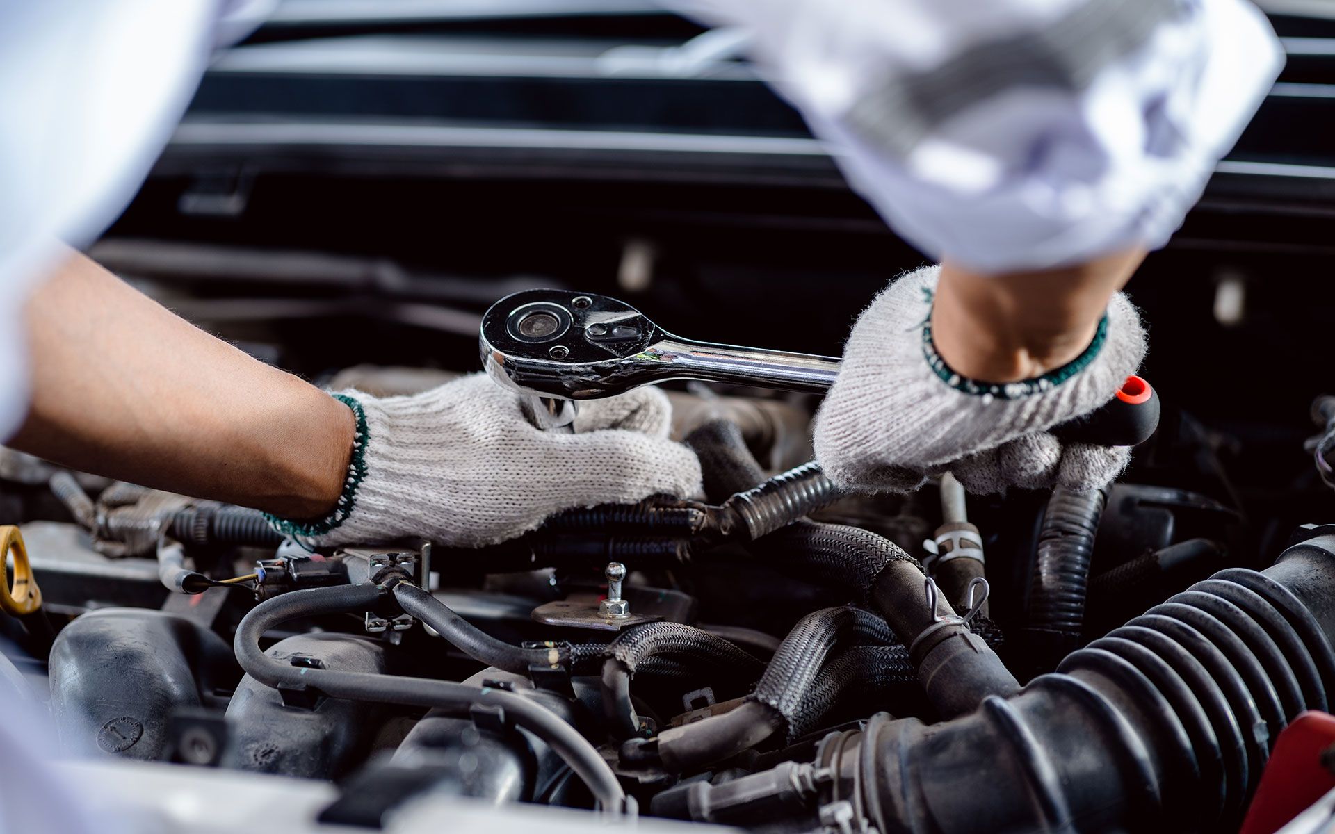 A man is working on a car engine with a wrench.