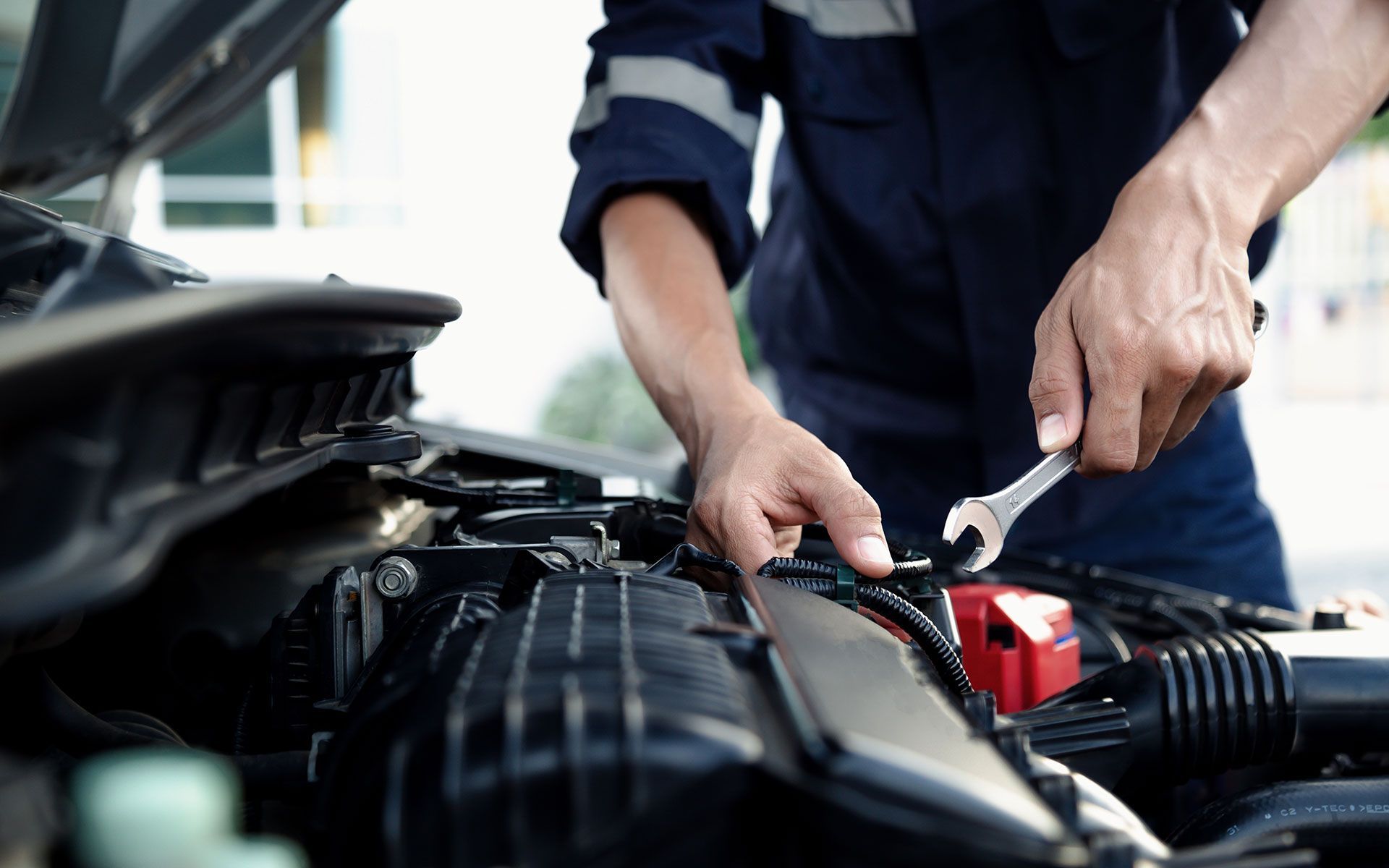 A man is working on the engine of a car with a wrench.