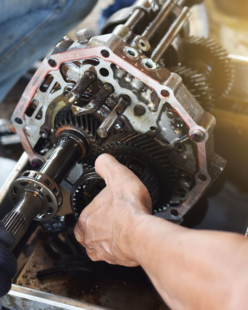 A man is working on a gearbox in a garage.