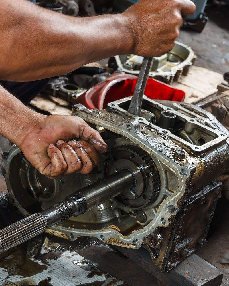 A man is working on a gearbox with a wrench.