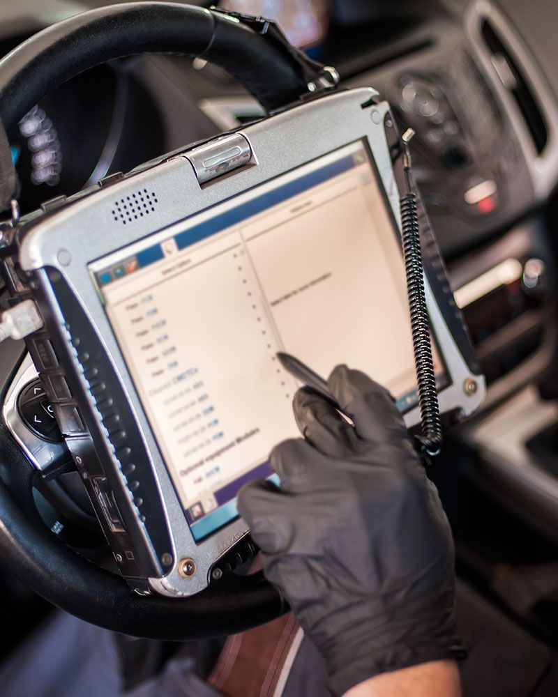 A person wearing black gloves is using a tablet in a car