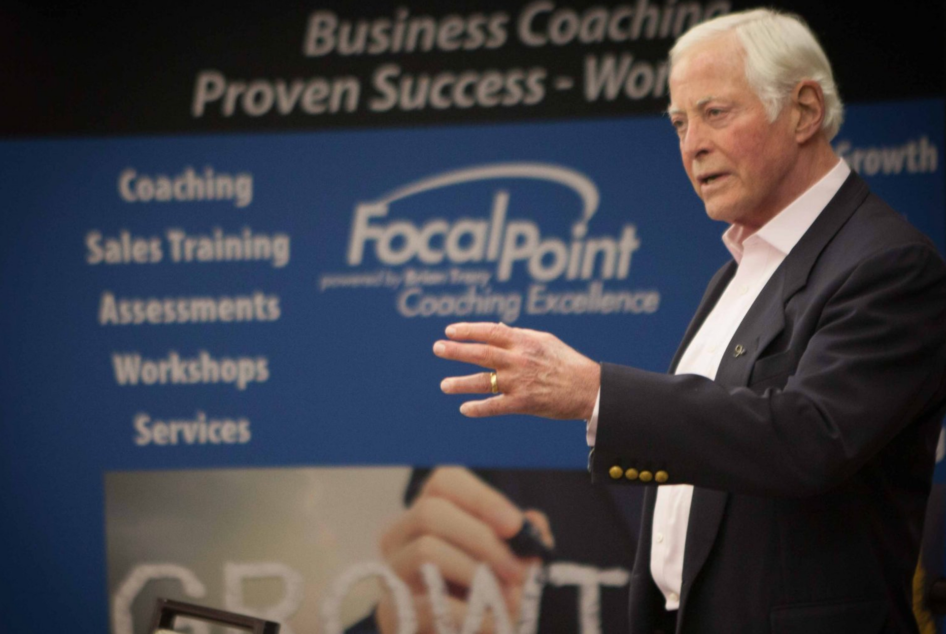 Brian Tracy speaking in front of Focal Point sign