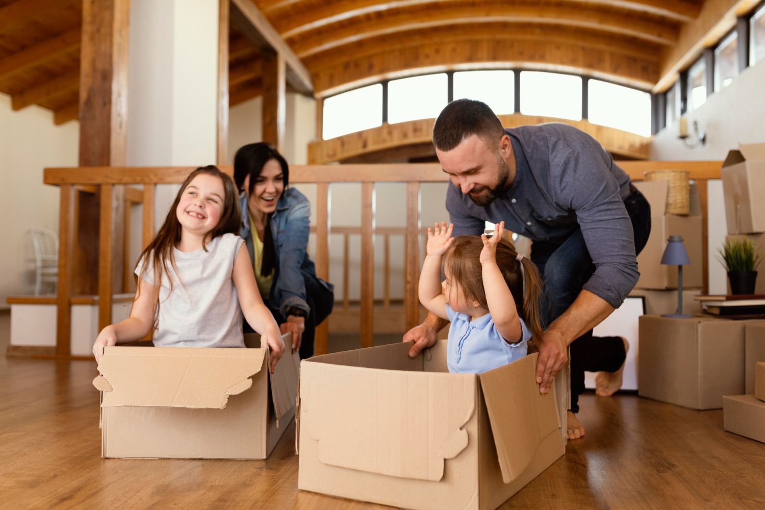 Family plays with children in cardboard boxes in their new home.