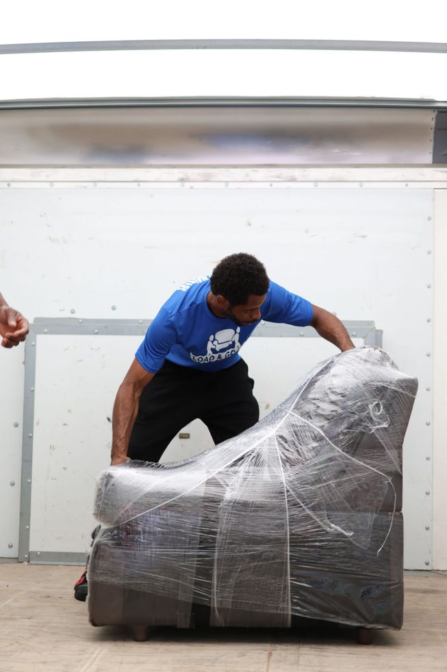 two men are carrying a large item on a dolly in a kitchen .