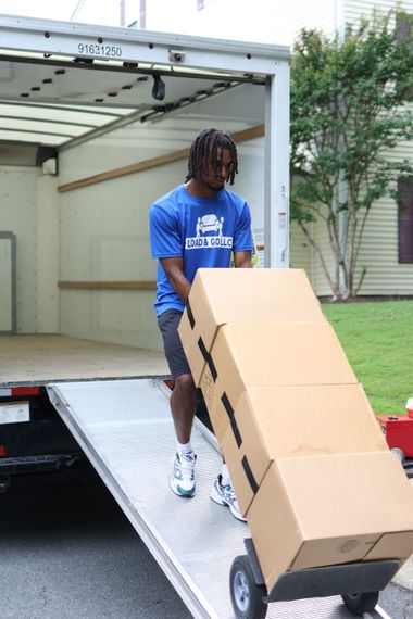 two men are wrapping a couch in plastic wrap in a living room .