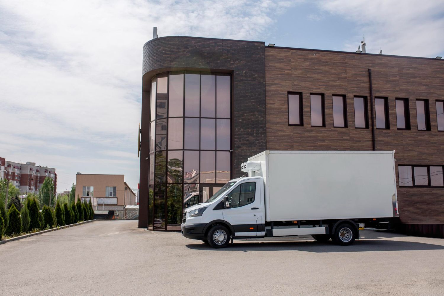 Two movers in orange jumpsuits lift a beige couch indoors, smiling.