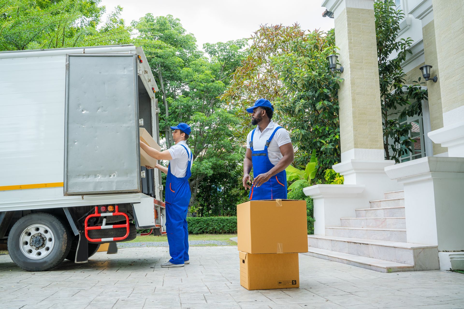 two men are loading boxes into a moving truck .