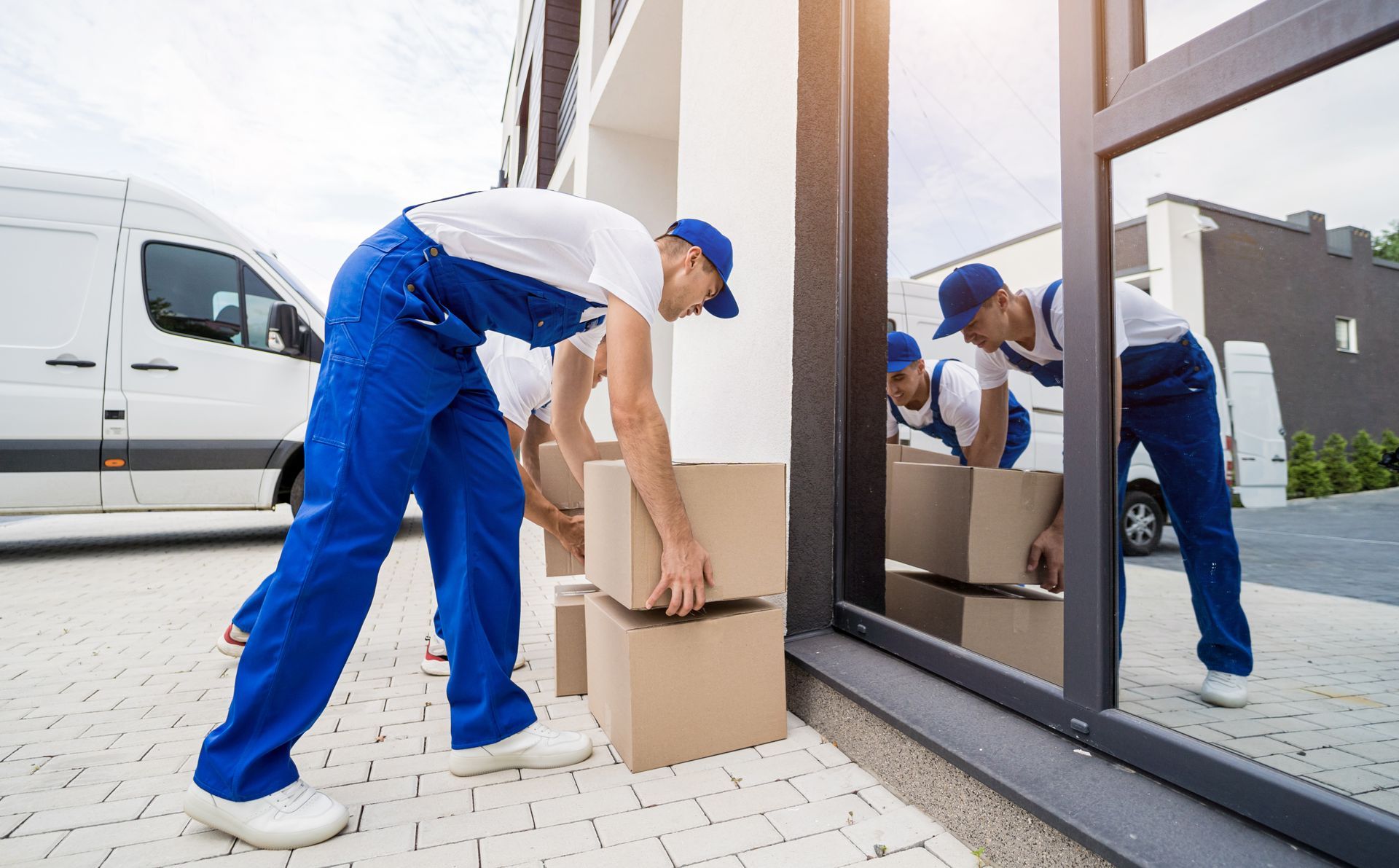 A man is lifting a cardboard box in front of a building.