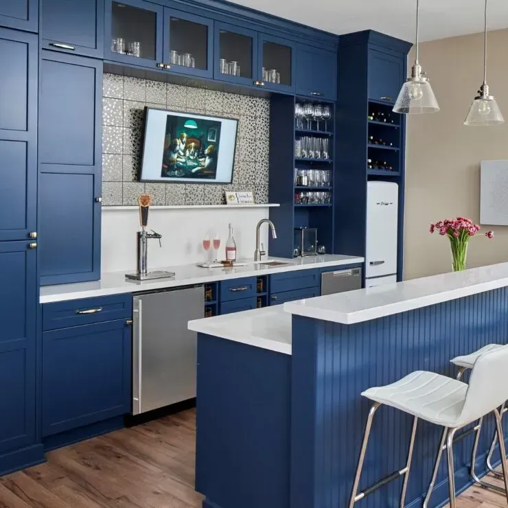 Blue home bar with cabinets, countertop, sink, TV, and bar stools.