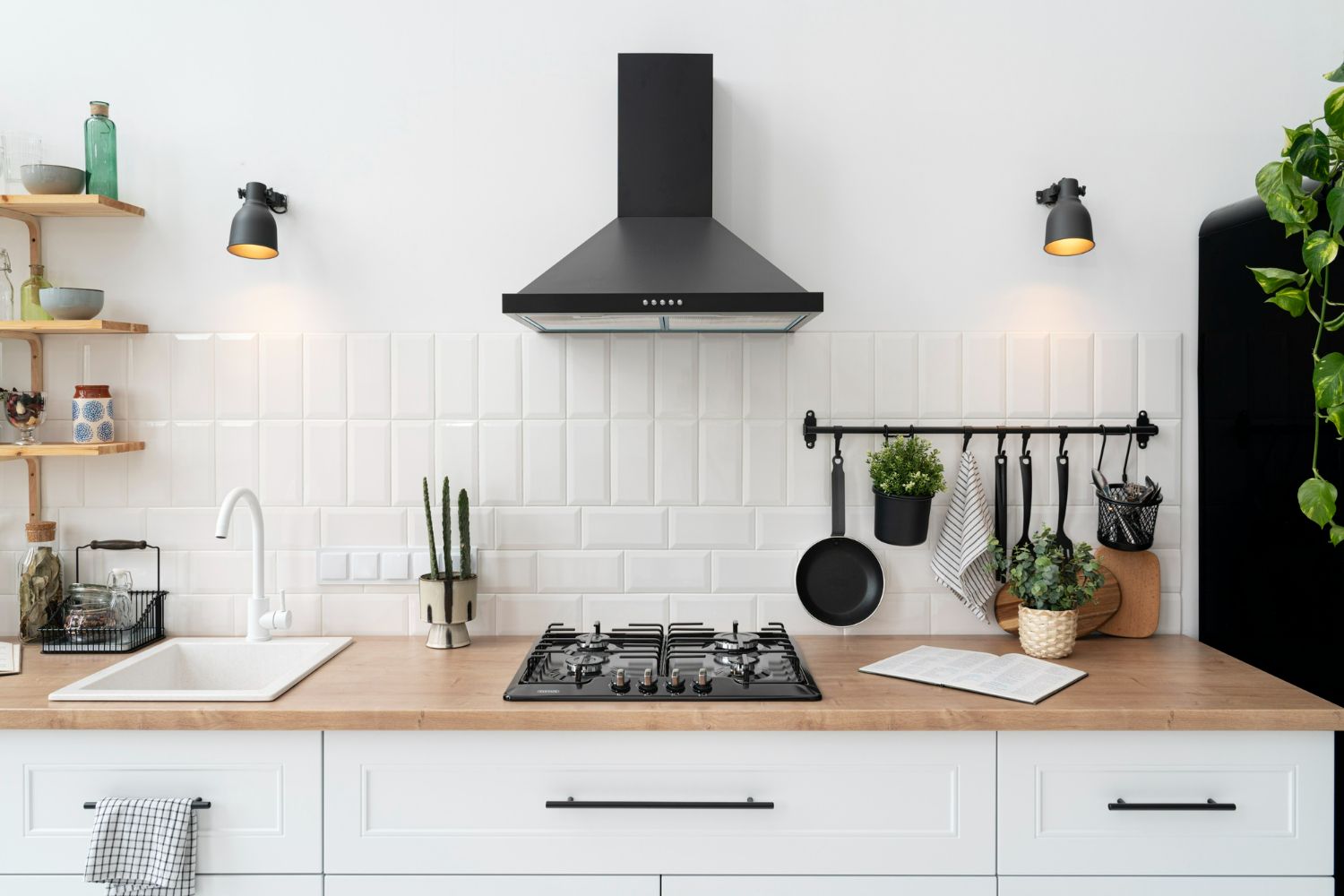 Modern kitchen with a black range hood, stove, white cabinets, and wooden countertop.