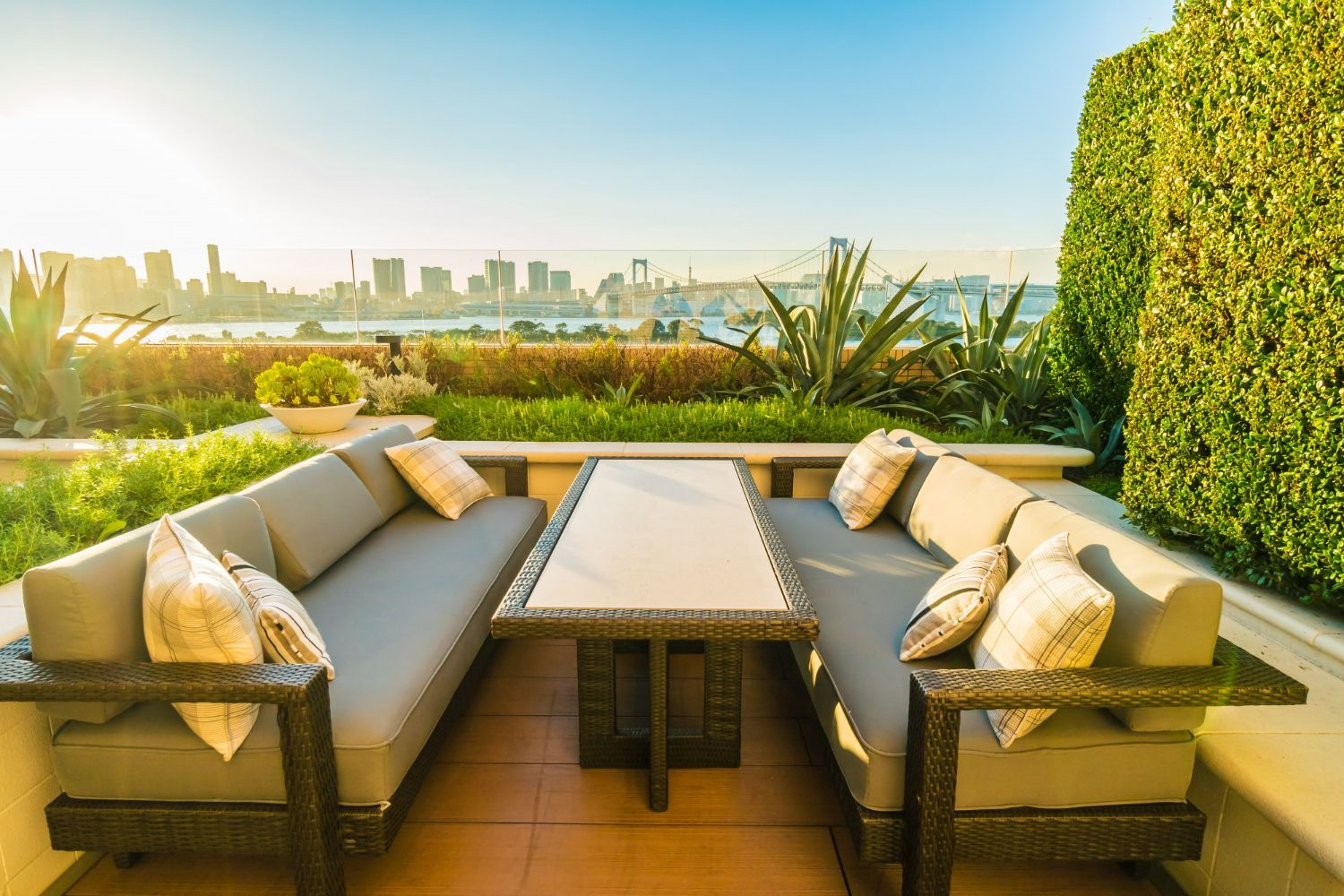 Outdoor patio with gray couches, a table, and city skyline view.