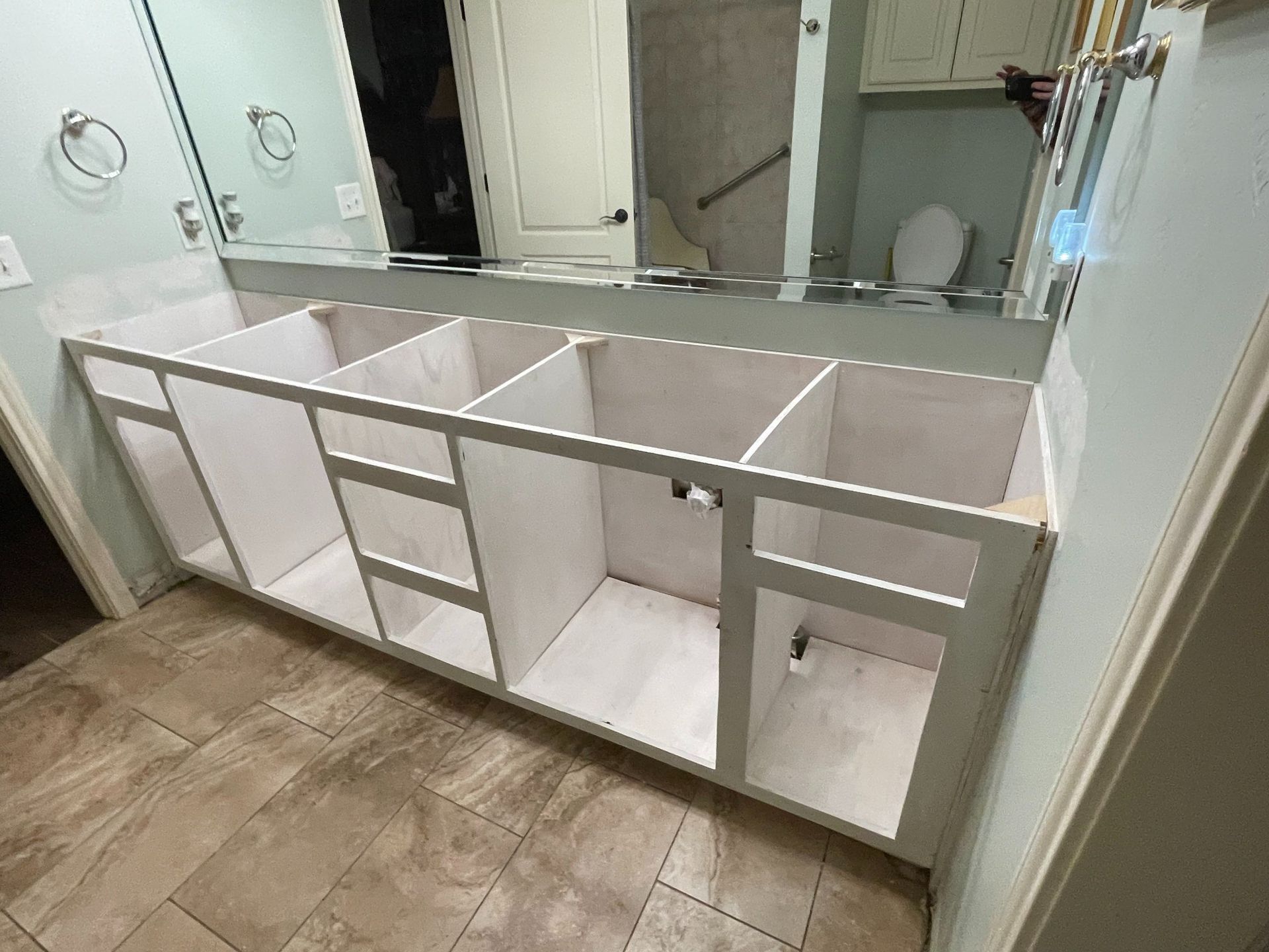 White unfinished bathroom vanity cabinet frame in a room, ready for installation.