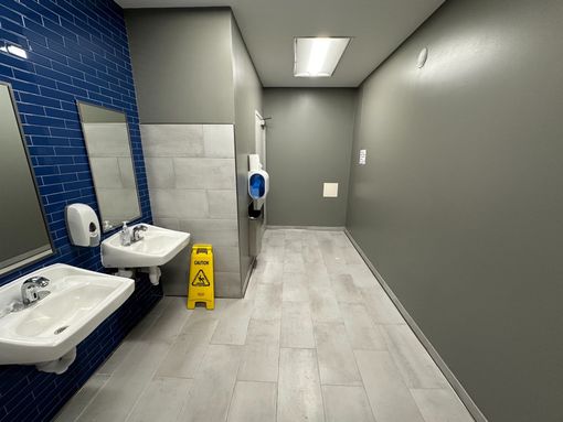 Public restroom with blue-tiled wall, sinks, mirrors, and a