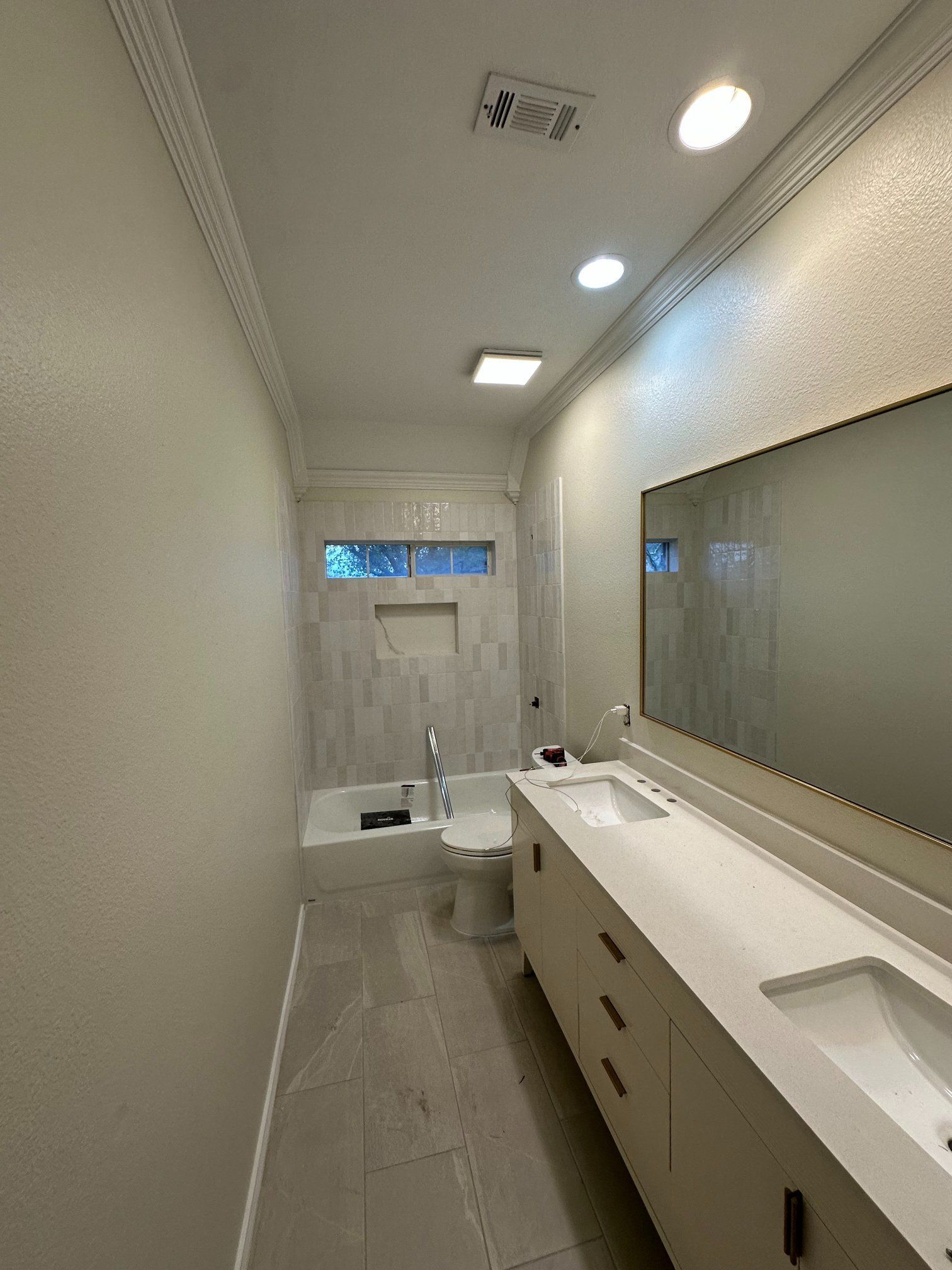 Bathroom with white vanity, large mirror, and tiled shower/bath area. Neutral walls and ceiling.
