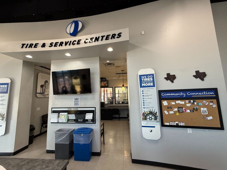 Entrance to a tire and service center with a television, signage, and a corkboard.