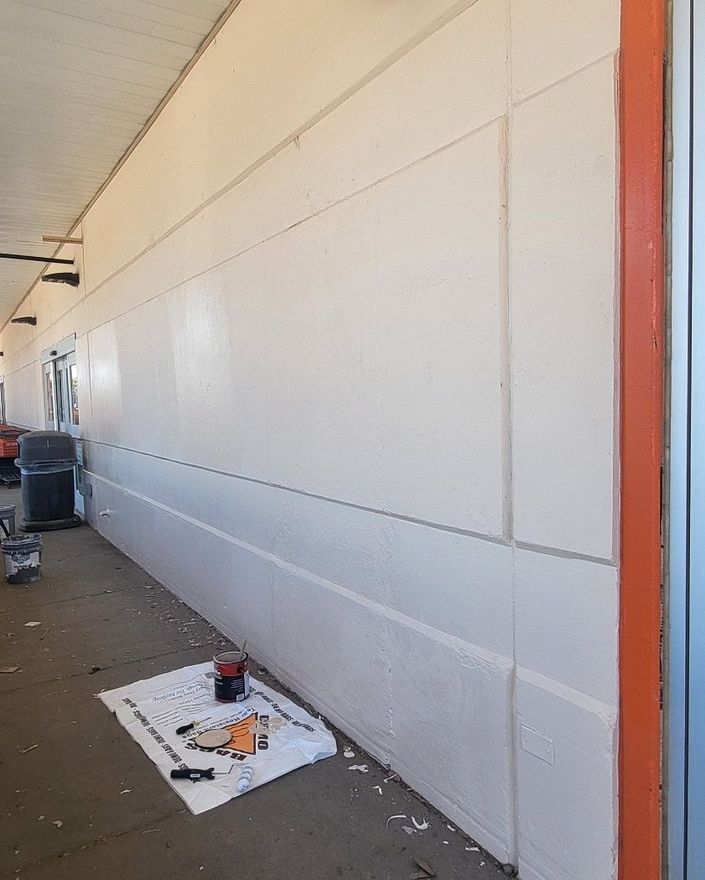 White wall with orange trim. Paint supplies on the ground.
