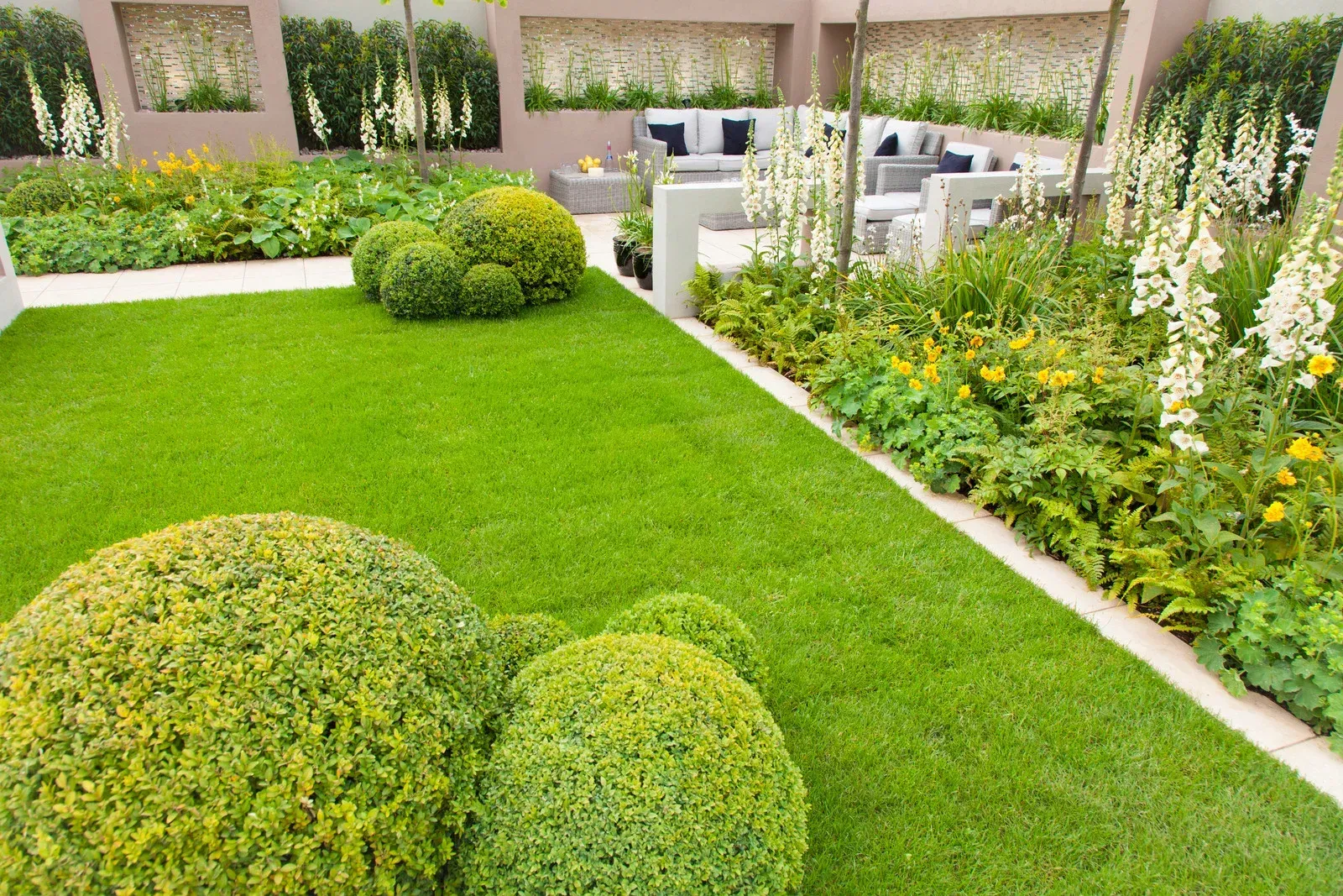 A lush green lawn with flowers and bushes in a garden.
