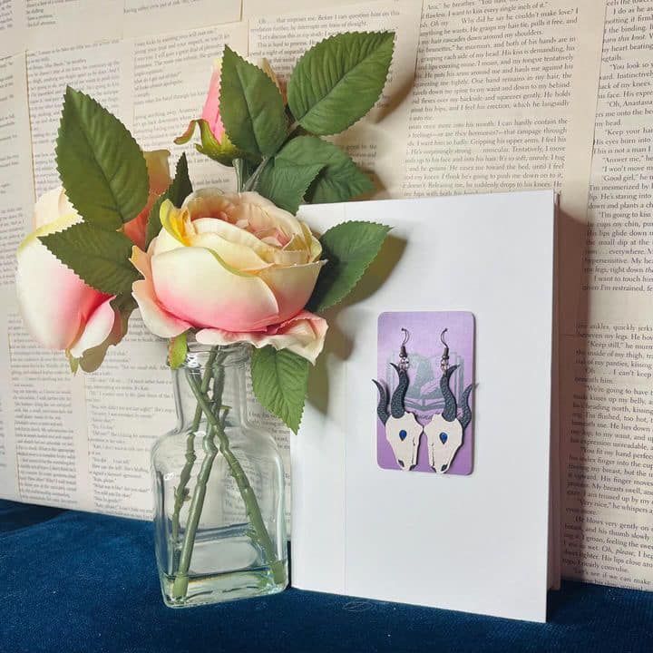 A vase of flowers next to a card with a pair of earrings on it