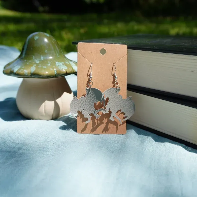 A pair of gargoyle earrings on a card next to a stack of books