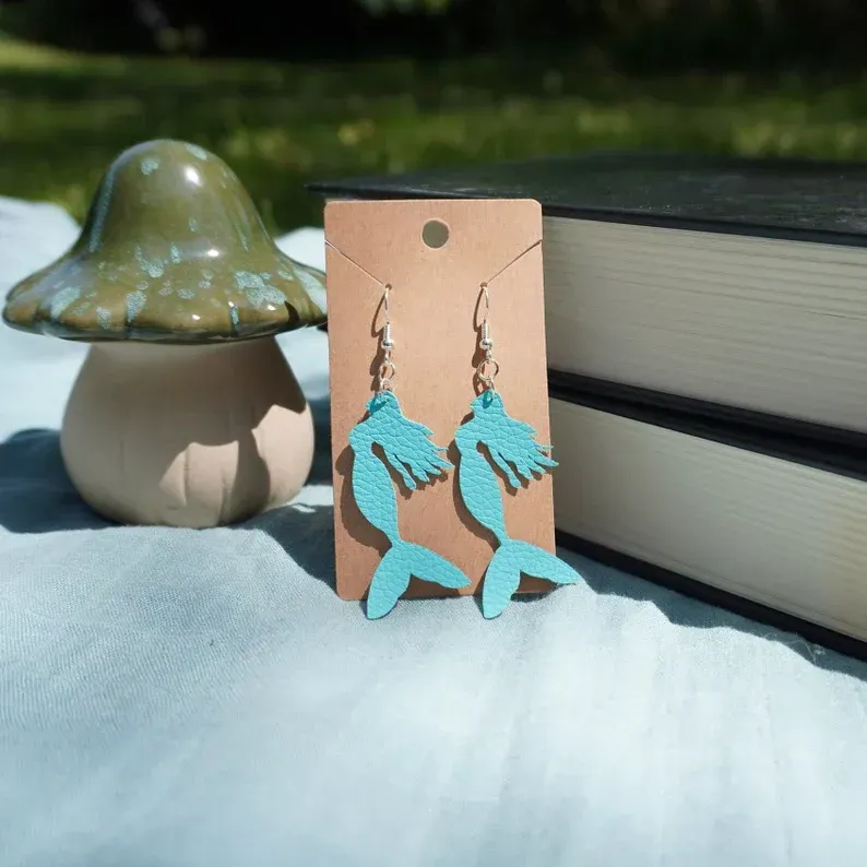 A pair of blue mermaid earrings on a card