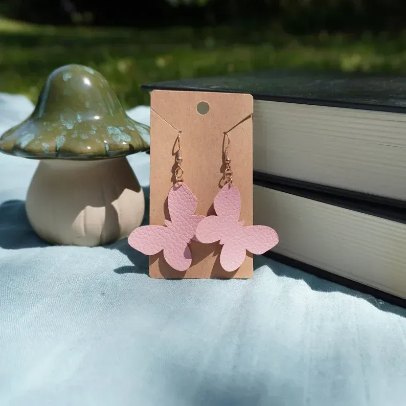 A pair of pink butterfly earrings on a card