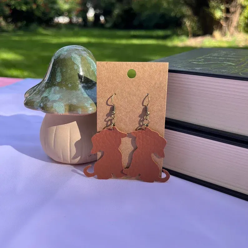 A pair of dog earrings are sitting on a table next to a mushroom and books.