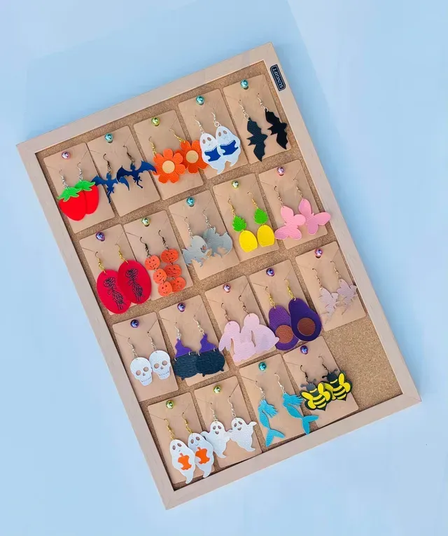 A wooden display case filled with a variety of earrings