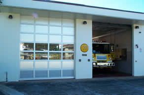 A fire truck is parked in a garage with its doors open.
