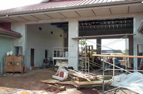 A building under construction with a red roof and scaffolding in front of it.
