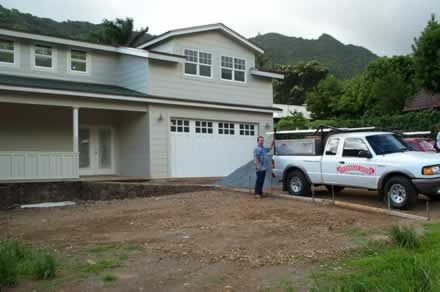 A man is standing in front of a house with a truck parked in front of it.