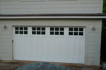 A white garage door with a lot of windows on a house.