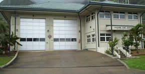 A large white house with two garage doors and a driveway leading to it.