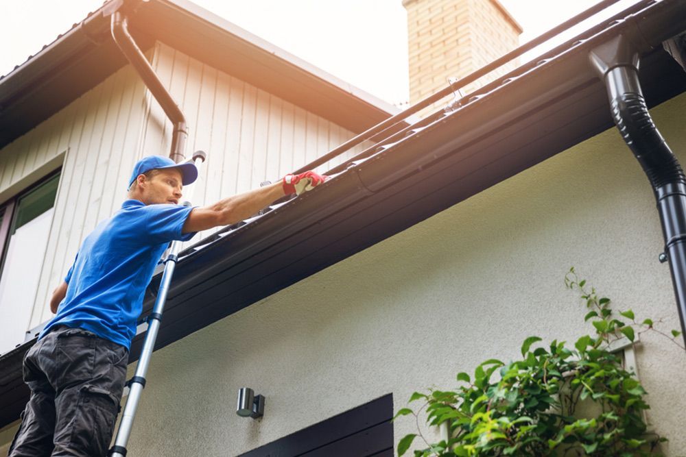 Man using the ladder to clean the gutter — Handyman in Sussex Inlet, NSW