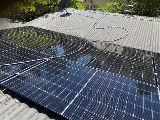 A Person Is Cleaning A Solar Panel With A Spray Bottle — Gutter Cleaning In Shoalhaven, NSW