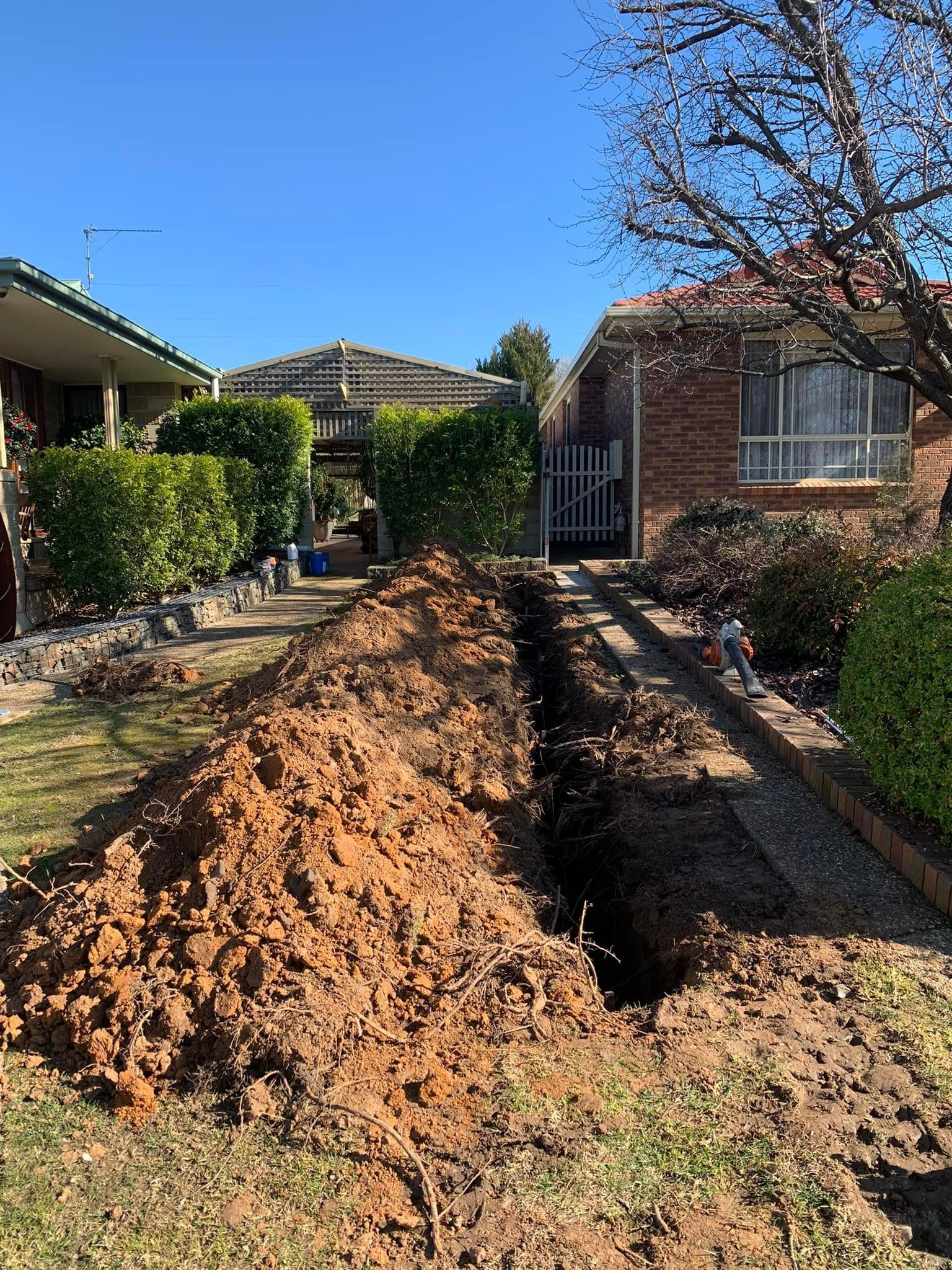Trench Dug in a Front Yard With a Pile of Dirt Beside It — Riverina Tree Fellas In Cootamundra, NSW