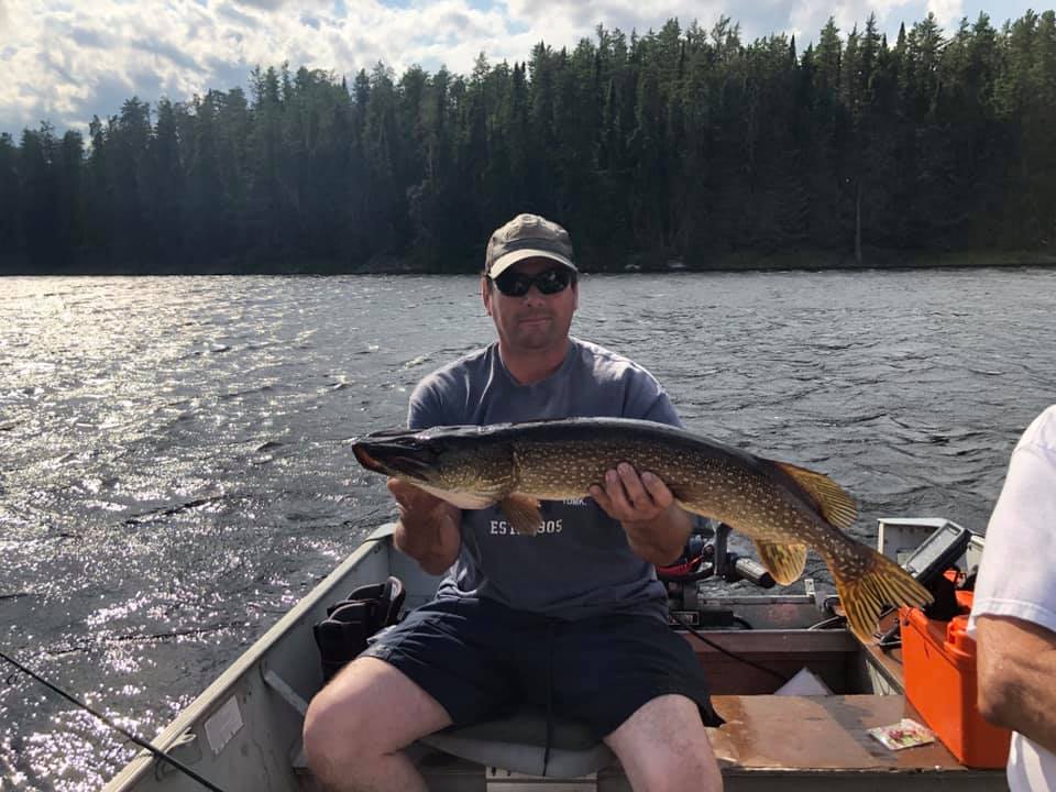 A man is sitting in a boat holding a large fish.