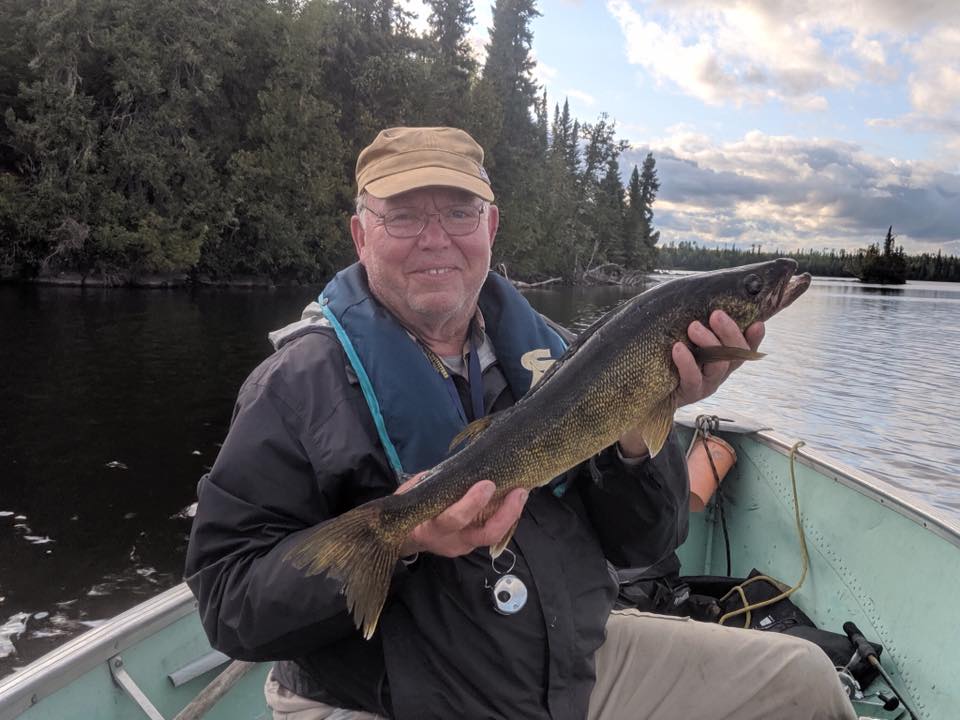 A man in a boat is holding a large fish in his hands.